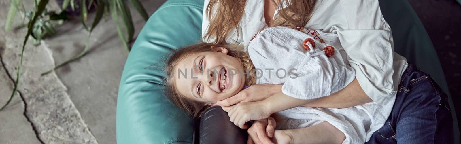 Happy caucasian mother with young beautiful cheerful daughter are having time together
