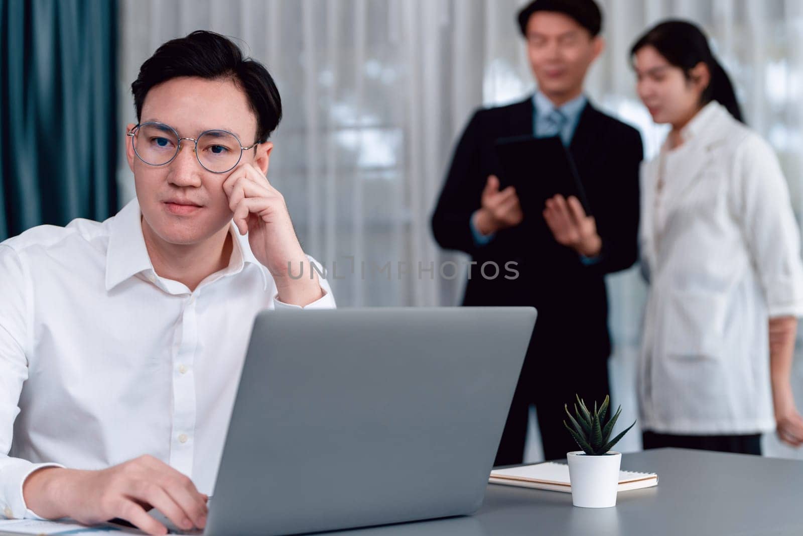 Portrait of focus young successful confident male manager, executive wearing business wear in harmony office arm crossed with blurred meeting background of colleagues, office worker.