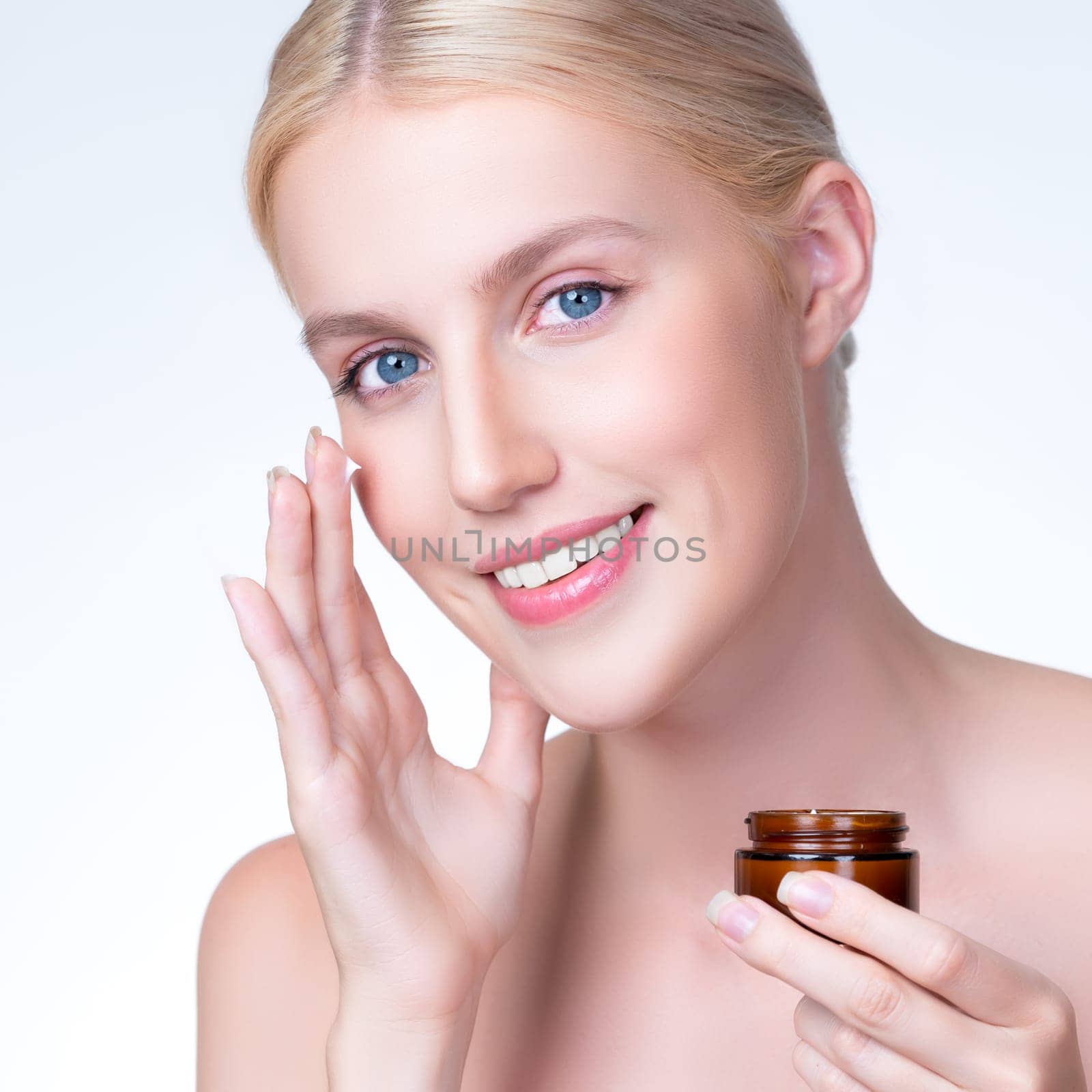 Closeup personable woman applying moisturizer cream on her face for perfect ski by biancoblue