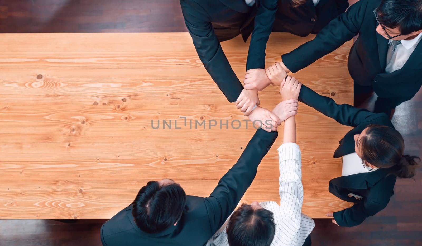 Top view cohesive group of business people join hands stack together, form circle over meeting table for copyspace. Colleagues working to promote harmony and synergy team building concept in workplace