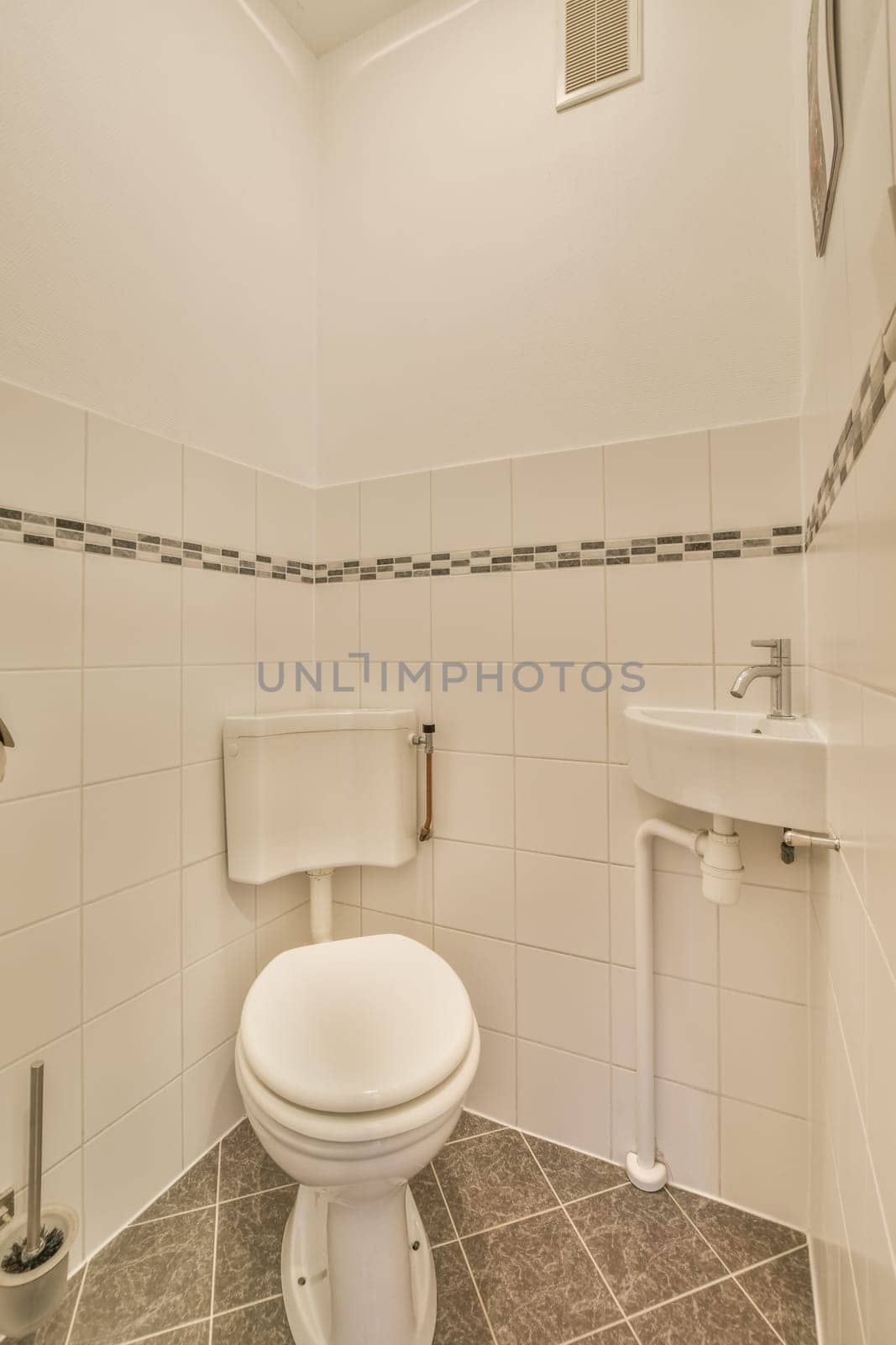 a white toilet in a small bathroom with tile flooring and walls that have black and white tiles on them