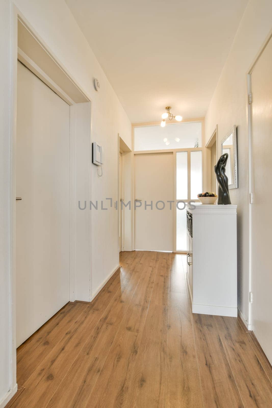 a hallway with white walls and wooden floors and a by casamedia