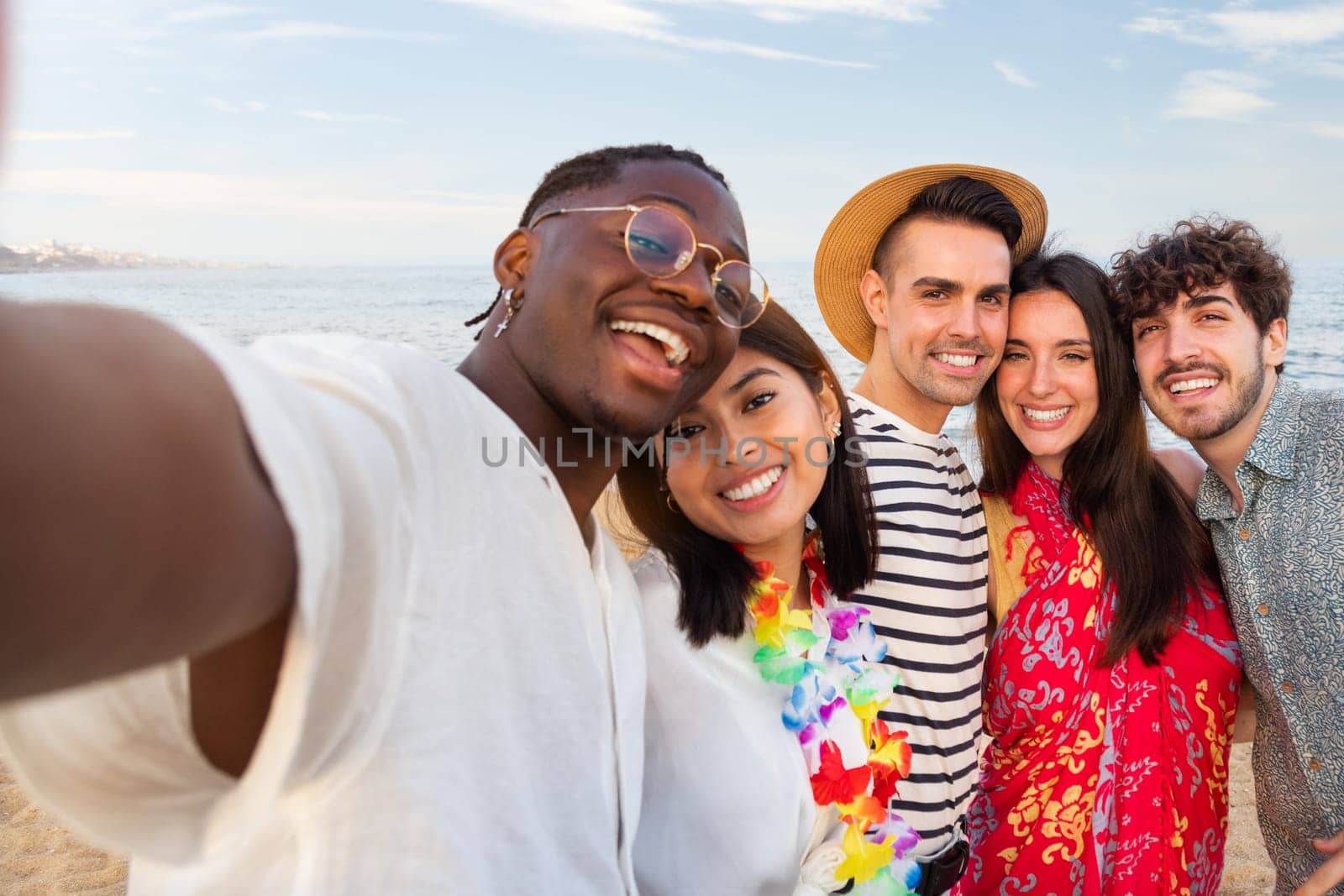 Group of happy, multiracial friends looking at camera take selfie together outdoors in the beach. Summer party. by Hoverstock