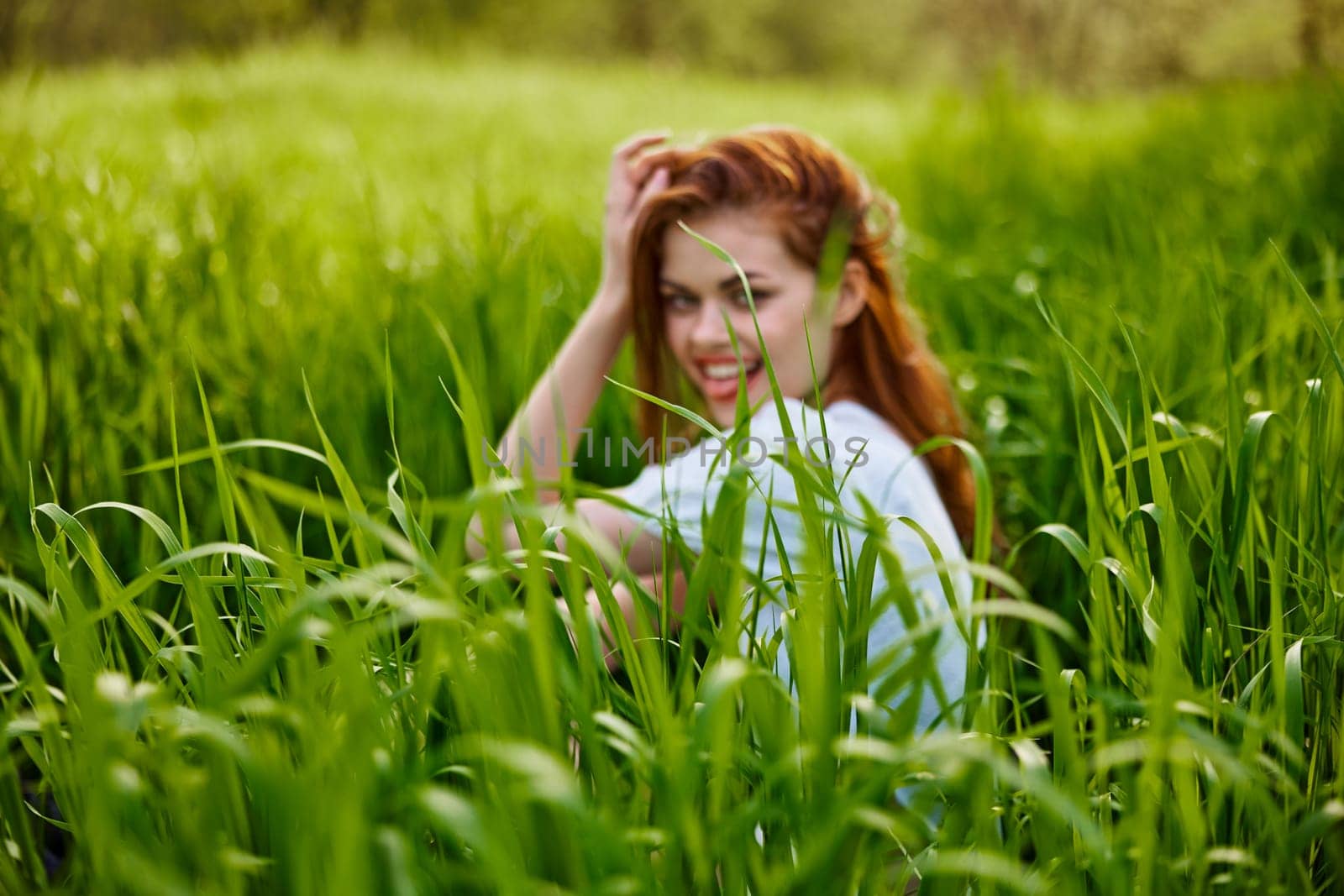 photograph of a woman sitting in the grass focusing on grass leaves. High quality photo