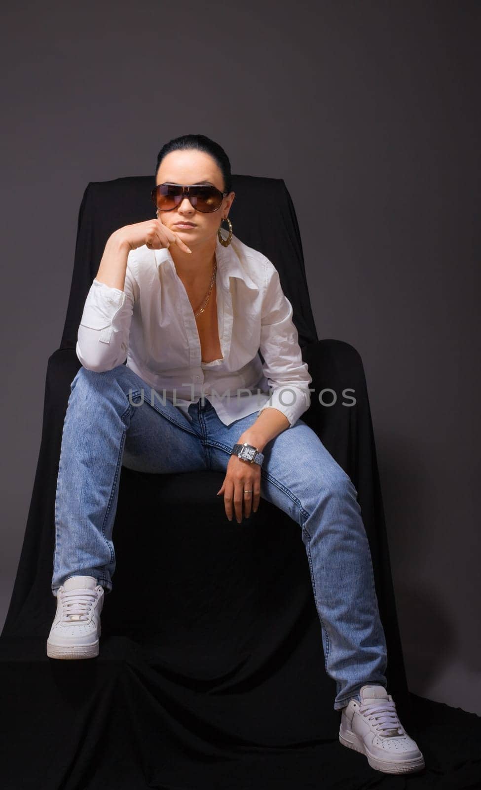 Young beauty woman sit in jeans and open shirt on black
