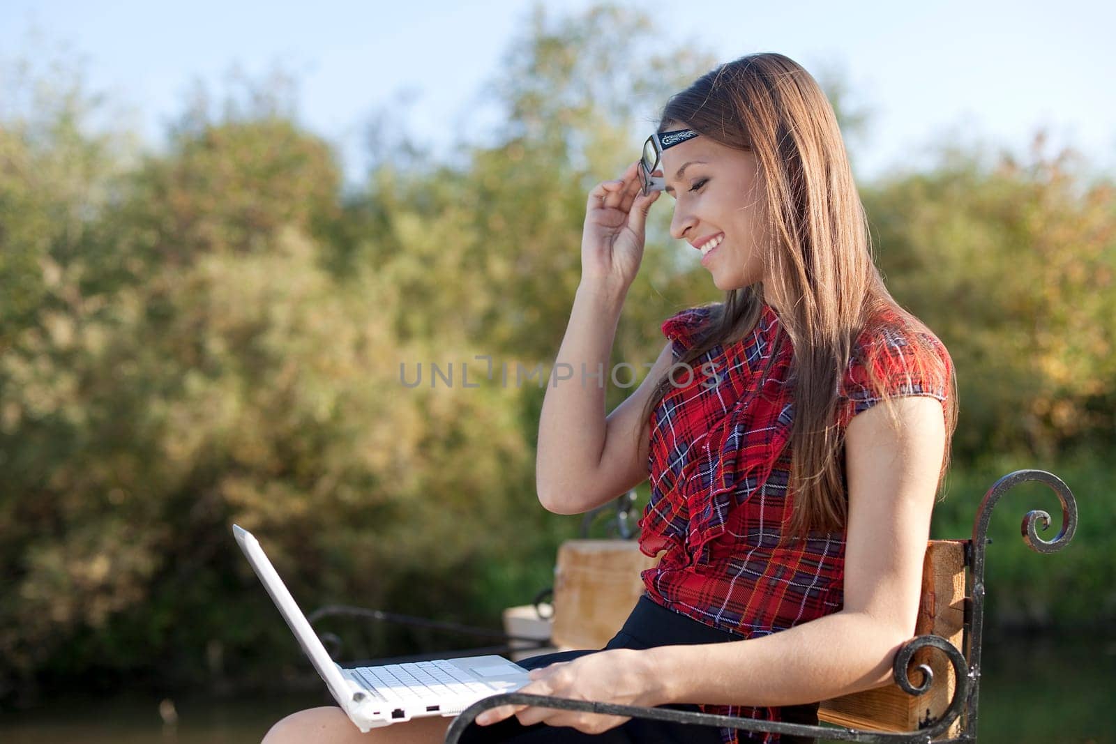 Girl on bench see on laptop in autumn park