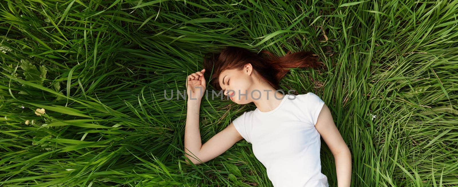 peaceful, happy woman lies in green tall grass by Vichizh