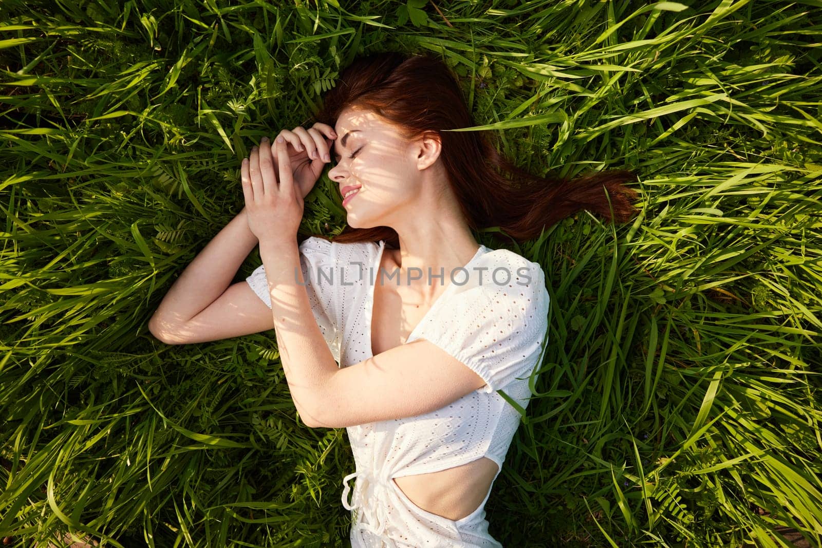 top view of a woman lying on the grass in a light dress. High quality photo