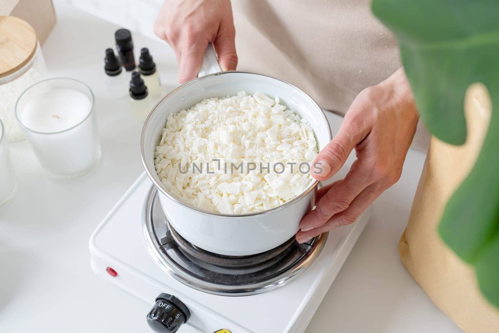 Creative hobby at home. Woman making decorative aroma candles at table, mixing soy wax with hands