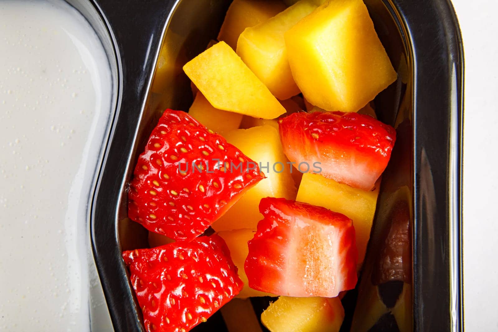 Portion of yogurt dessert with strawberry and mango in a plastic cup. High quality photo. Close-up.
