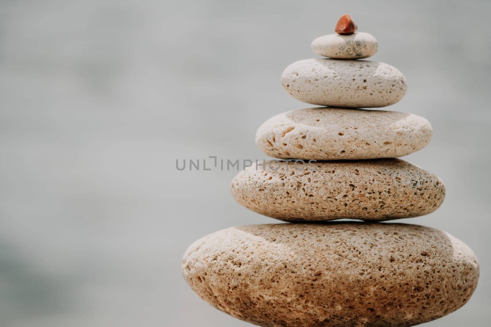 Pyramid stones on the seashore with warm sunset on the sea background. Happy holidays. Pebble beach, calm sea, travel destination. Concept of happy vacation on the sea, meditation, spa, calmness.