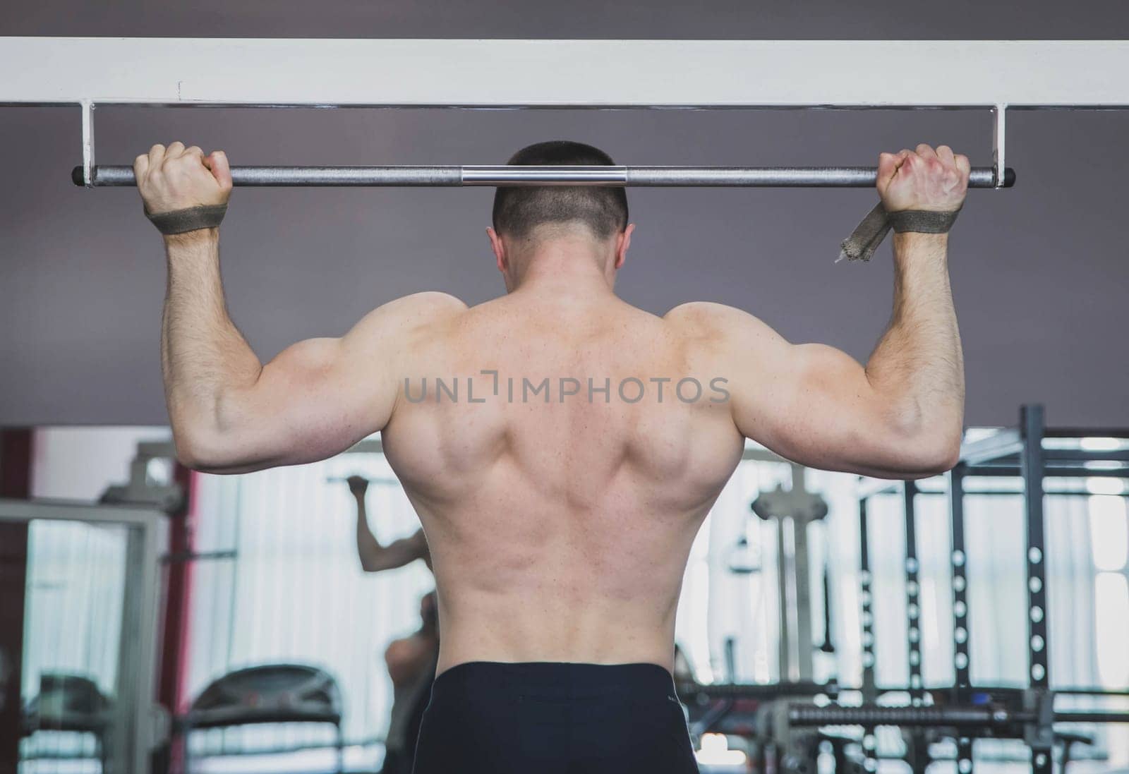 athlete pulls up in the gym fastening hands on the horizontal bar.