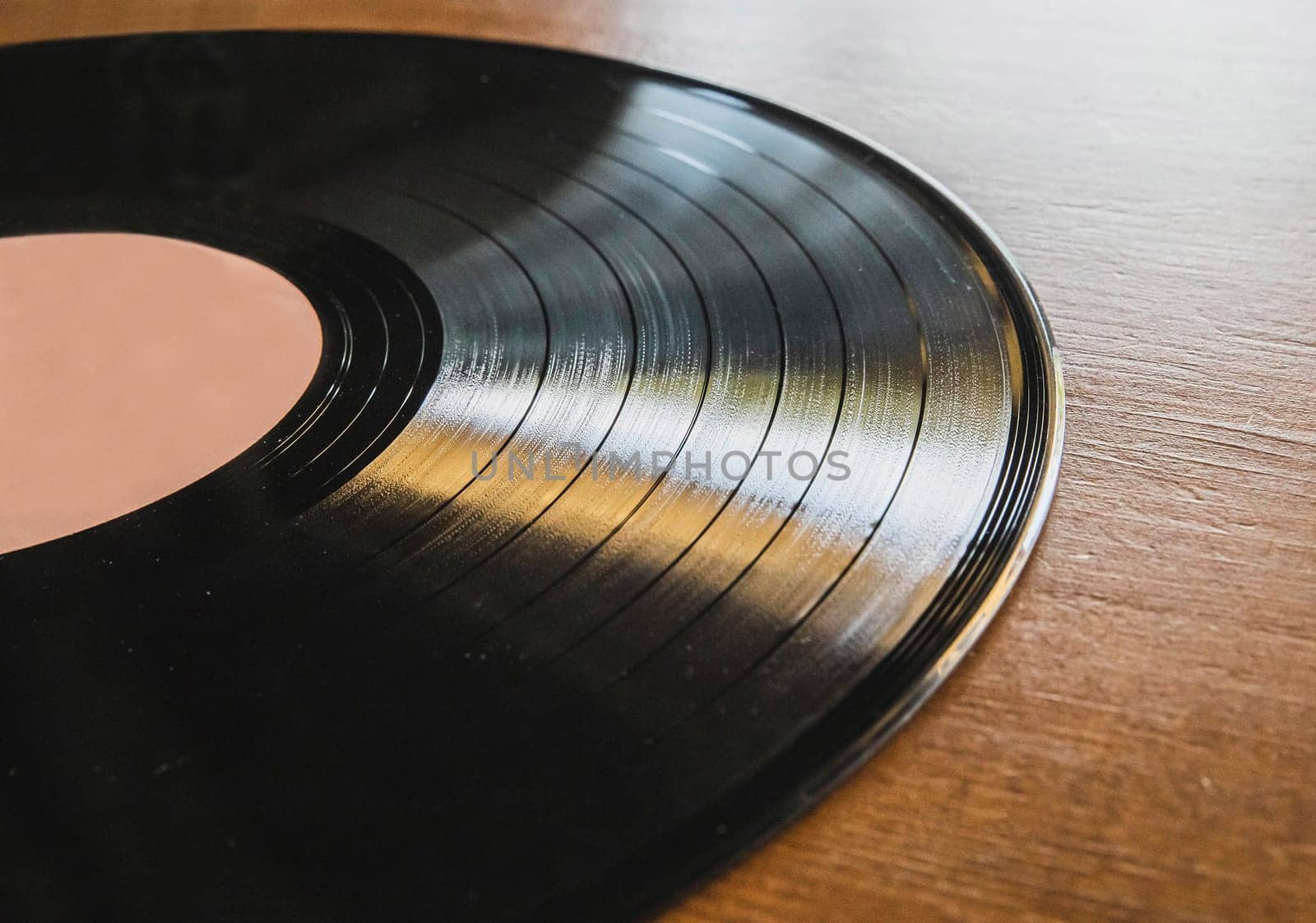 vinyl record lies on brown wooden table.