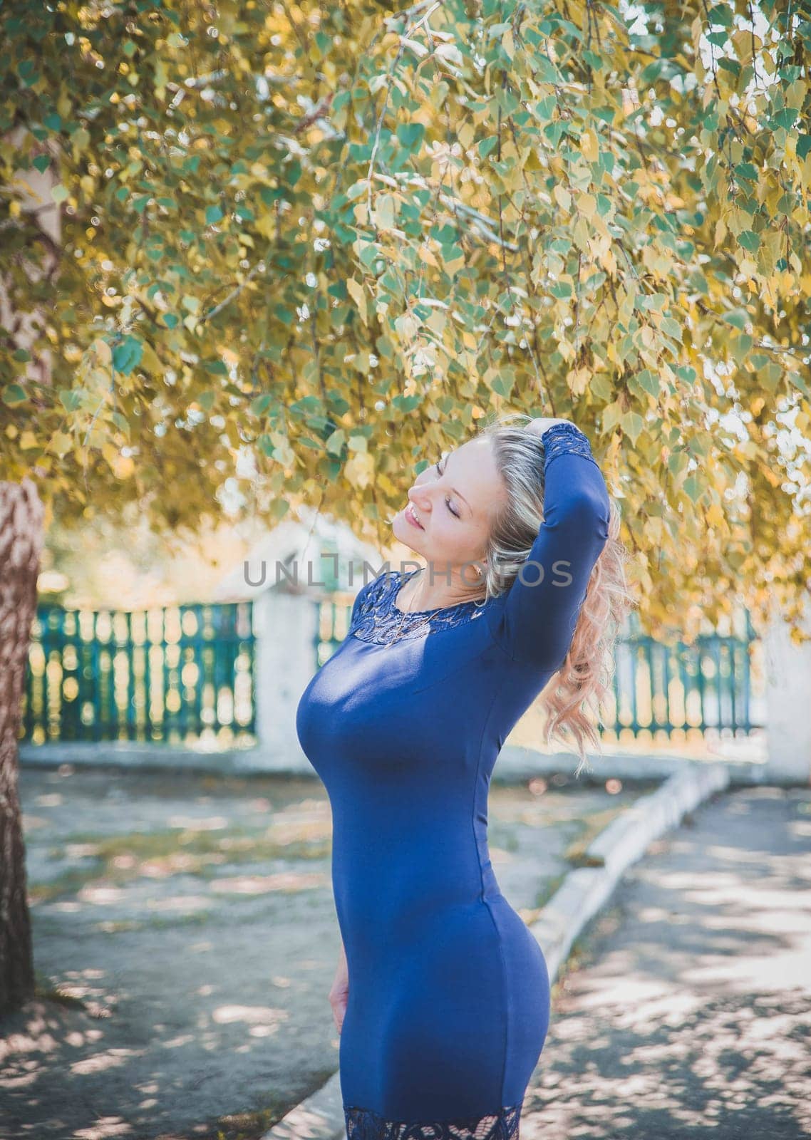 beautiful blonde in blue dress in the backyard in autumn.