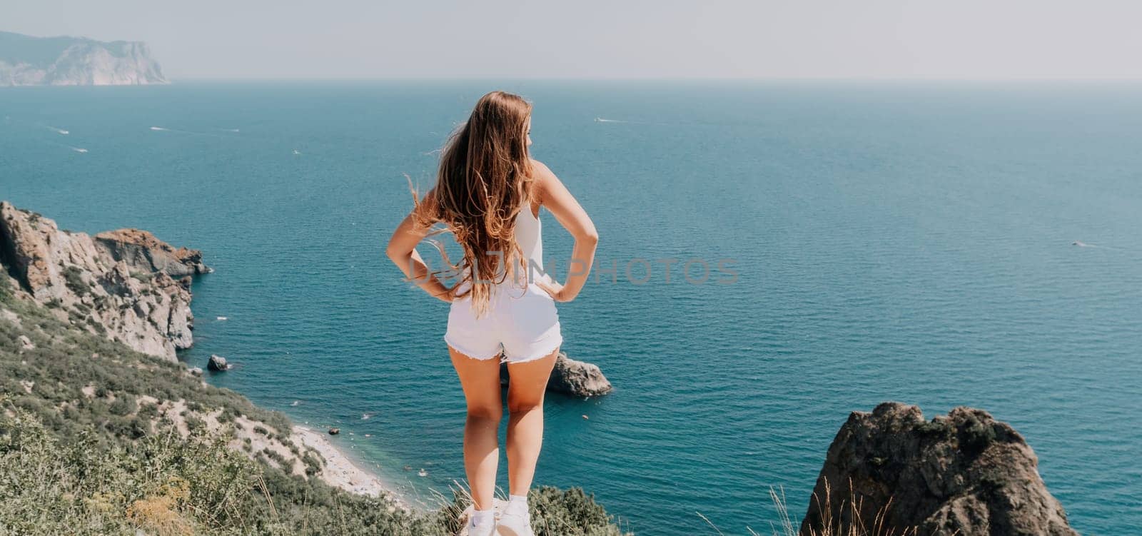 Woman summer travel sea. Happy tourist enjoy taking picture outdoors for memories. Woman traveler posing over sea bay surrounded by volcanic mountains, sharing travel adventure journey by panophotograph