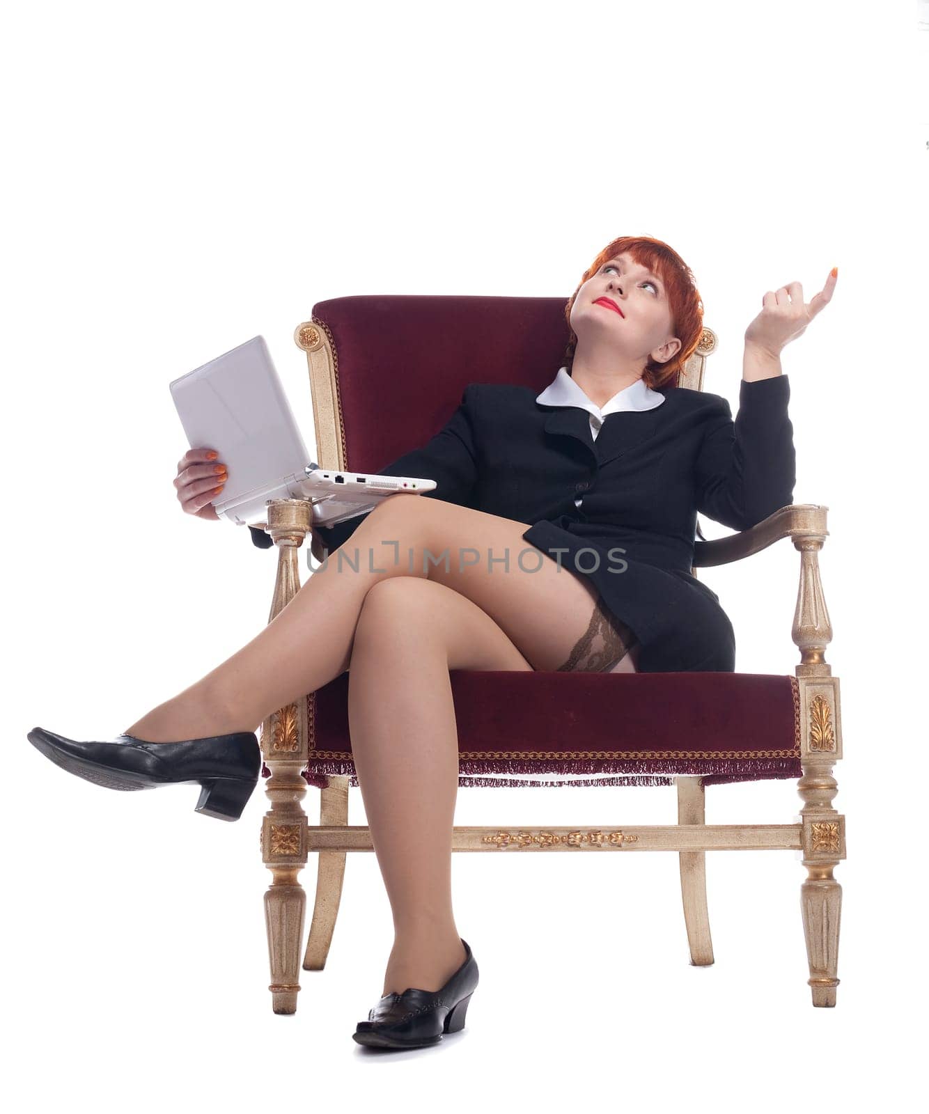 Red young woman in sexy business suit at old-fashion chair with laptop
