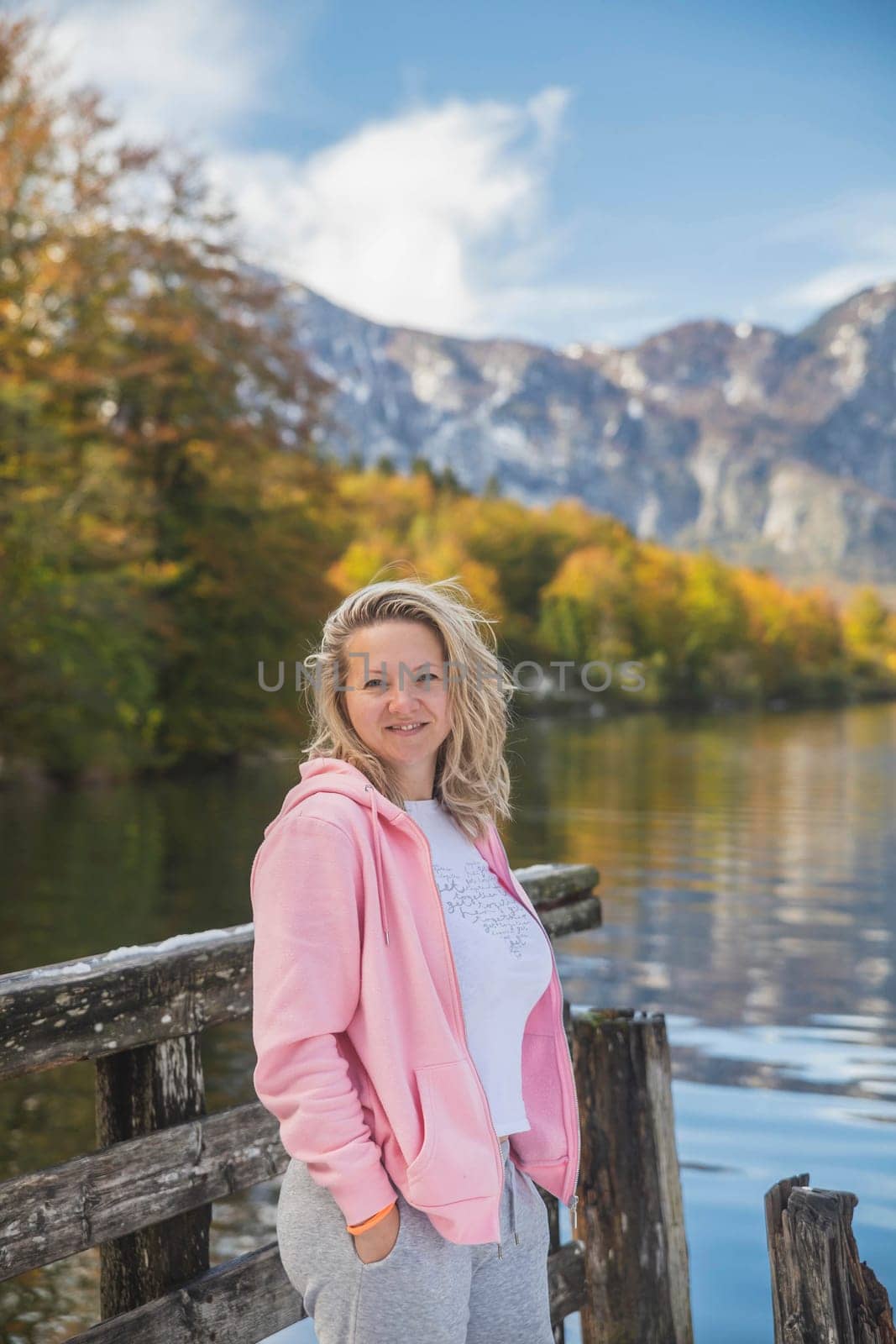 beautiful blonde girl stands near Lake Bohinj in Slovenia.