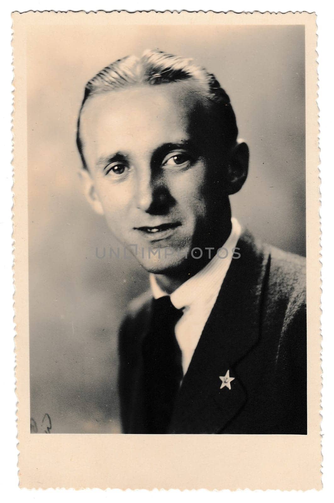 Retro photo shows studio portrait of young man. Man wears pin badge - Red Communist Star. Vintage black and white photography. by roman_nerud