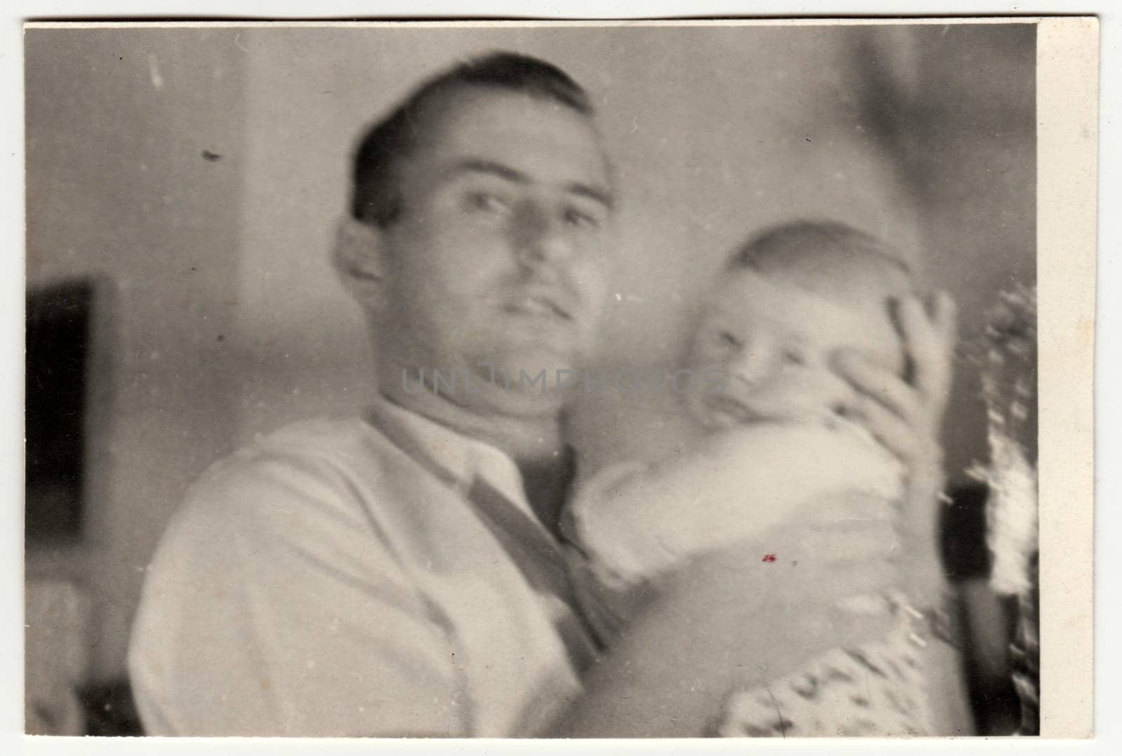 THE CZECHOSLOVAK SOCIALIST REPUBLIC - CIRCA 1950s: Retro photo shows father and toddler. Vintage black and white photography. With original film grain, blur and scratches.