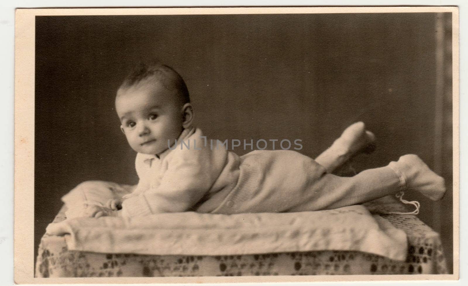 BEROUN, THE CZECHOSLOVAK REPUBLIC - MARCH 1, 1944: Retro photo shows toddler, lie prone. Vintage black and white photography.