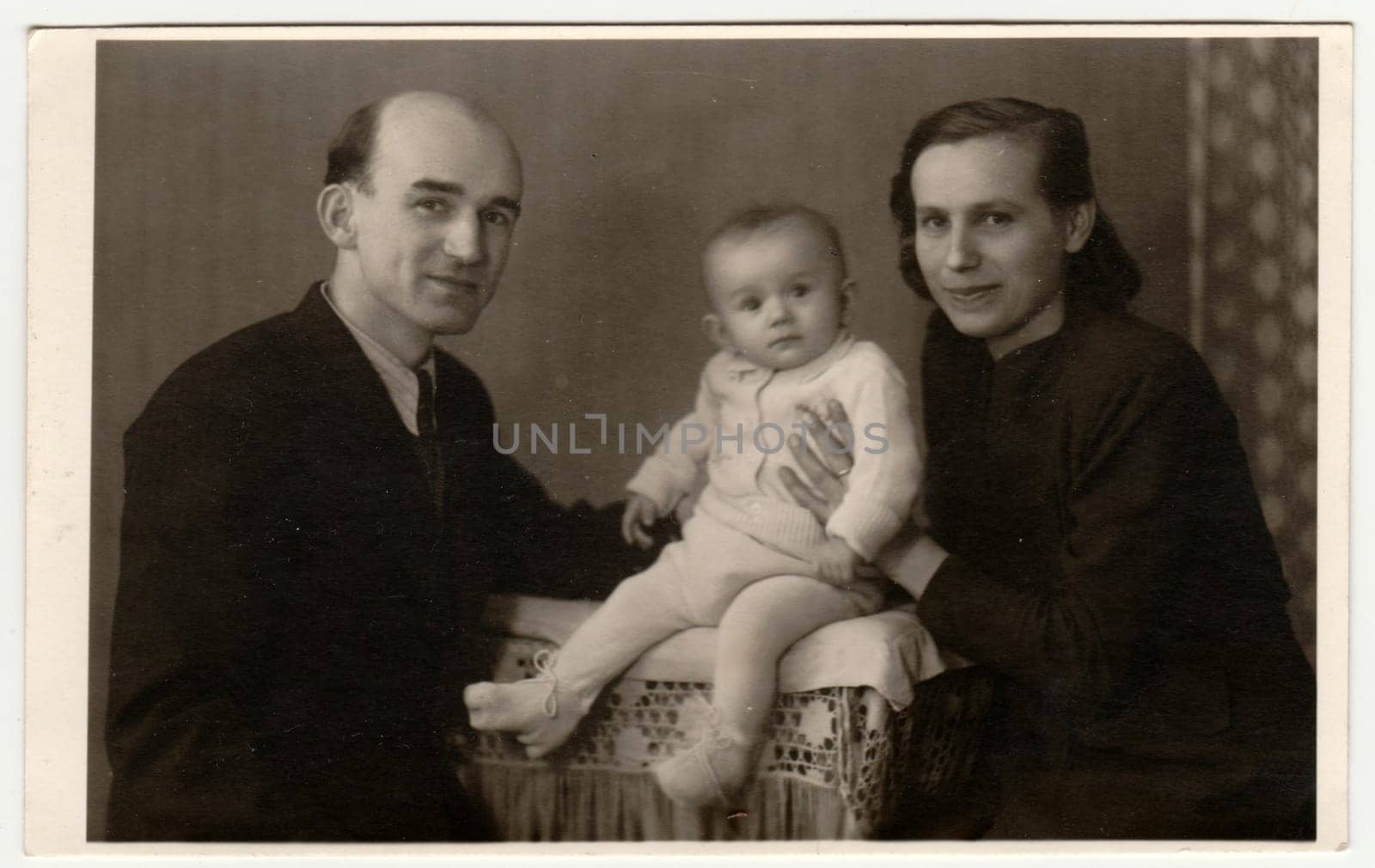 BEROUN, THE CZECHOSLOVAK REPUBLIC - MARCH 1, 1944: : Retro photo shows family with toddler. Vintage black and white photography.