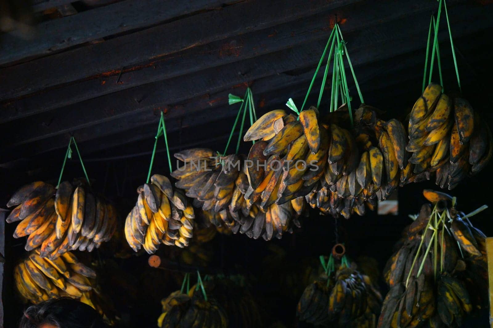Bunches of Ripe bananas hung on old wooden wall. Traditional kitchen in Indonesia.