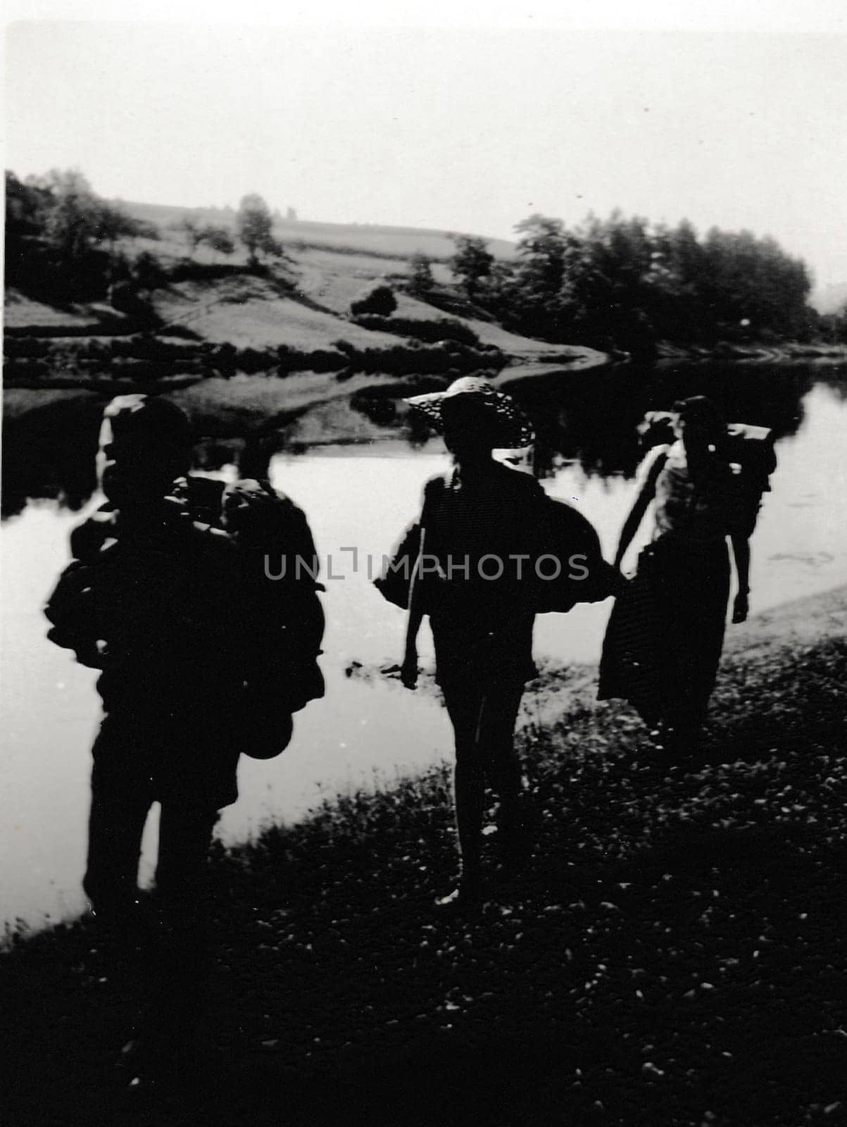 Retro photo shows tourists outside. Boys go alog the river bank. Vintage black and white photography. by roman_nerud