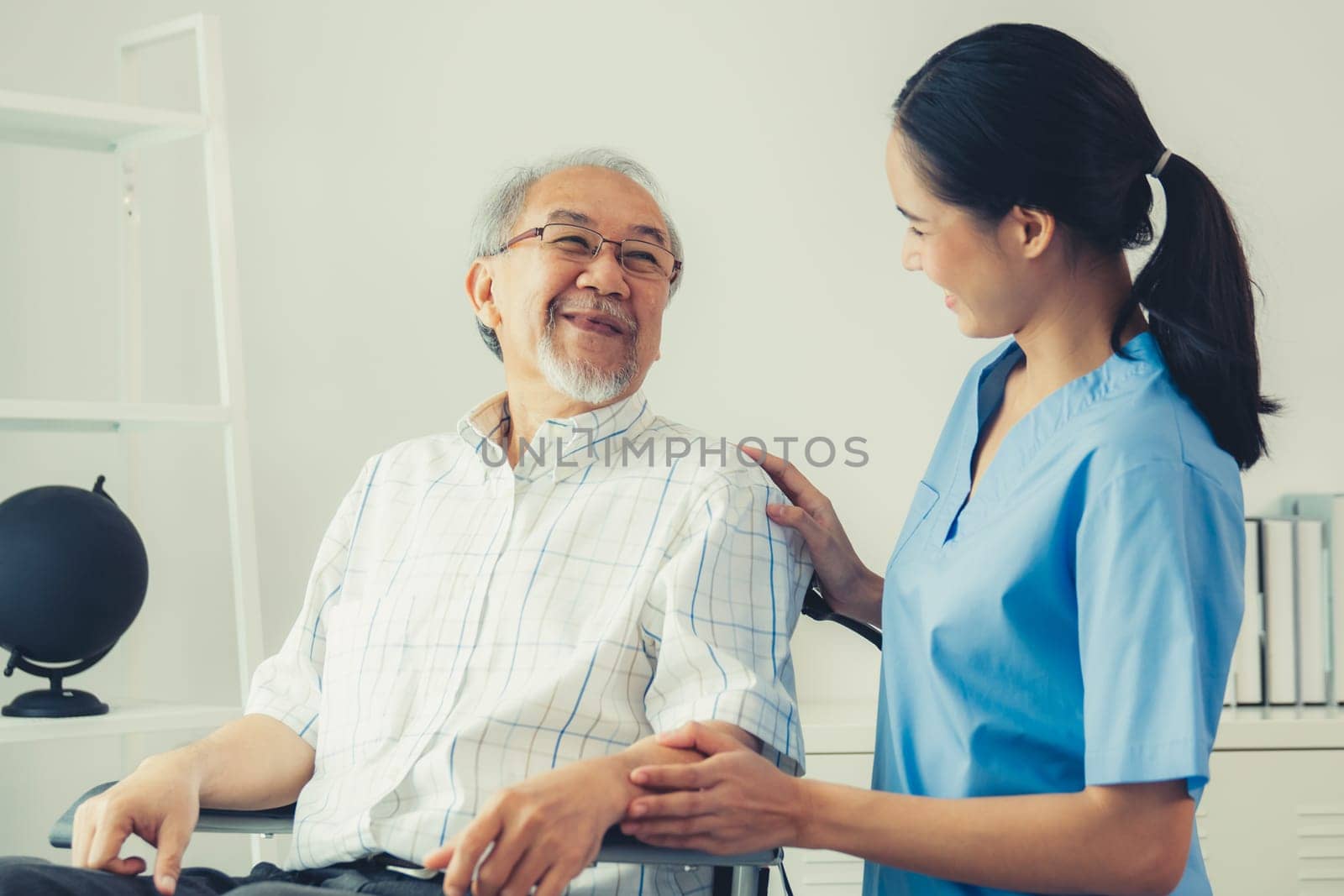 Happy positive asian nurse giving support and touching contented senior man with love. Nursing home for the elderly, elderly health and illness, senior patient carer.