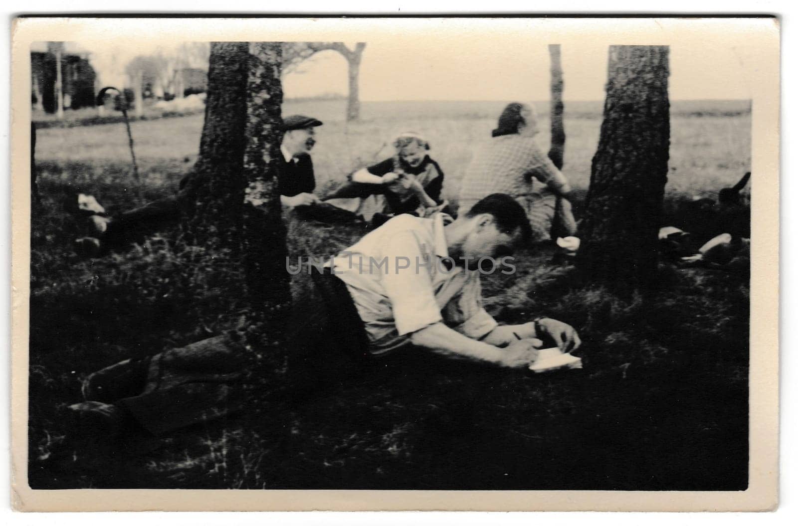 THE CZECHOSLOVAK SOCIALIST REPUBLIC - CIRCA 1950s: Retro photo shows tourists outside. Young man keeps the diary. Vintage black and white photography.