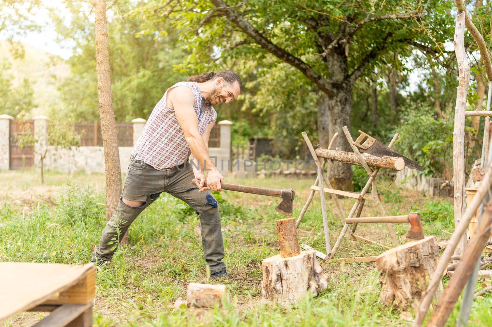 Strong man chopping wood with an axe in a garden
