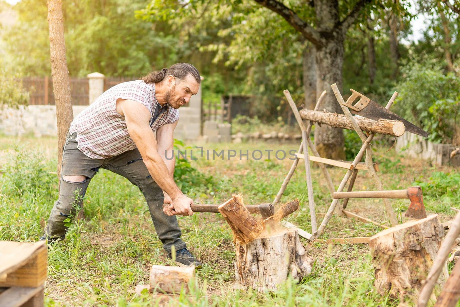 Strong male woodcutter chopping a log on a garden