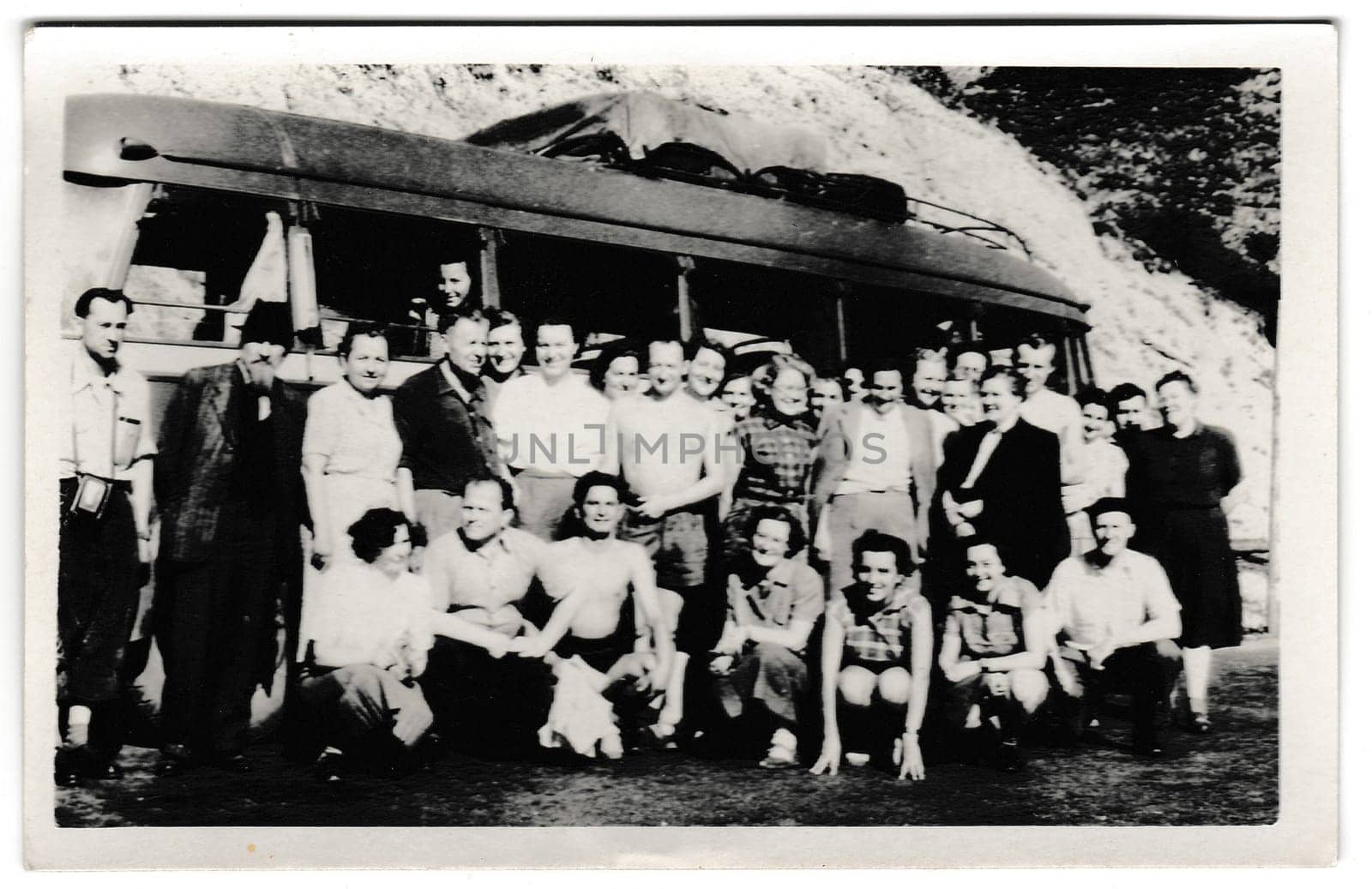 THE CZECHOSLOVAK SOCIALIST REPUBLIC - CIRCA 1950s: Retro photo shows tourists outside. Tourists pose in front of the bus. Summer - vacation theme. Vintage black and white photography.