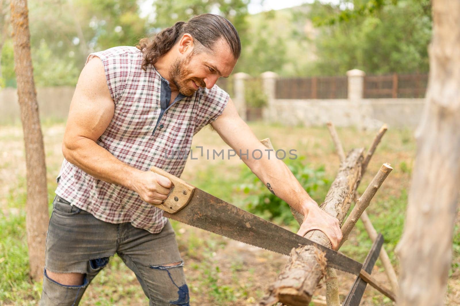 Close up portrait of a smiley woodcutter sawing wood in an garden