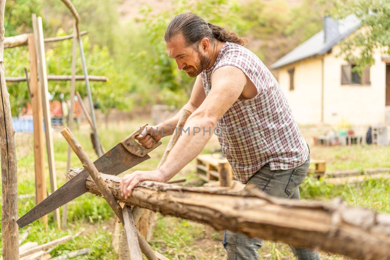 Strong adult Man cutting a log using a handsaw at an orchid at home