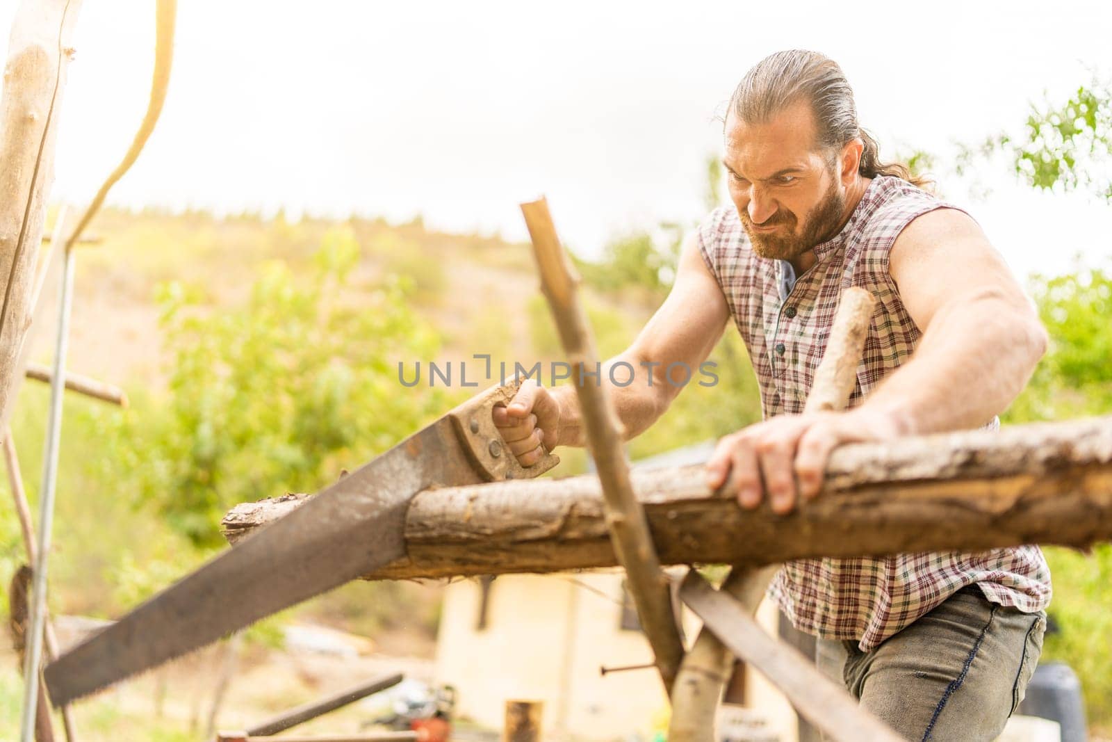 Portrait of a man making an effort to cut down a log with a hand saw