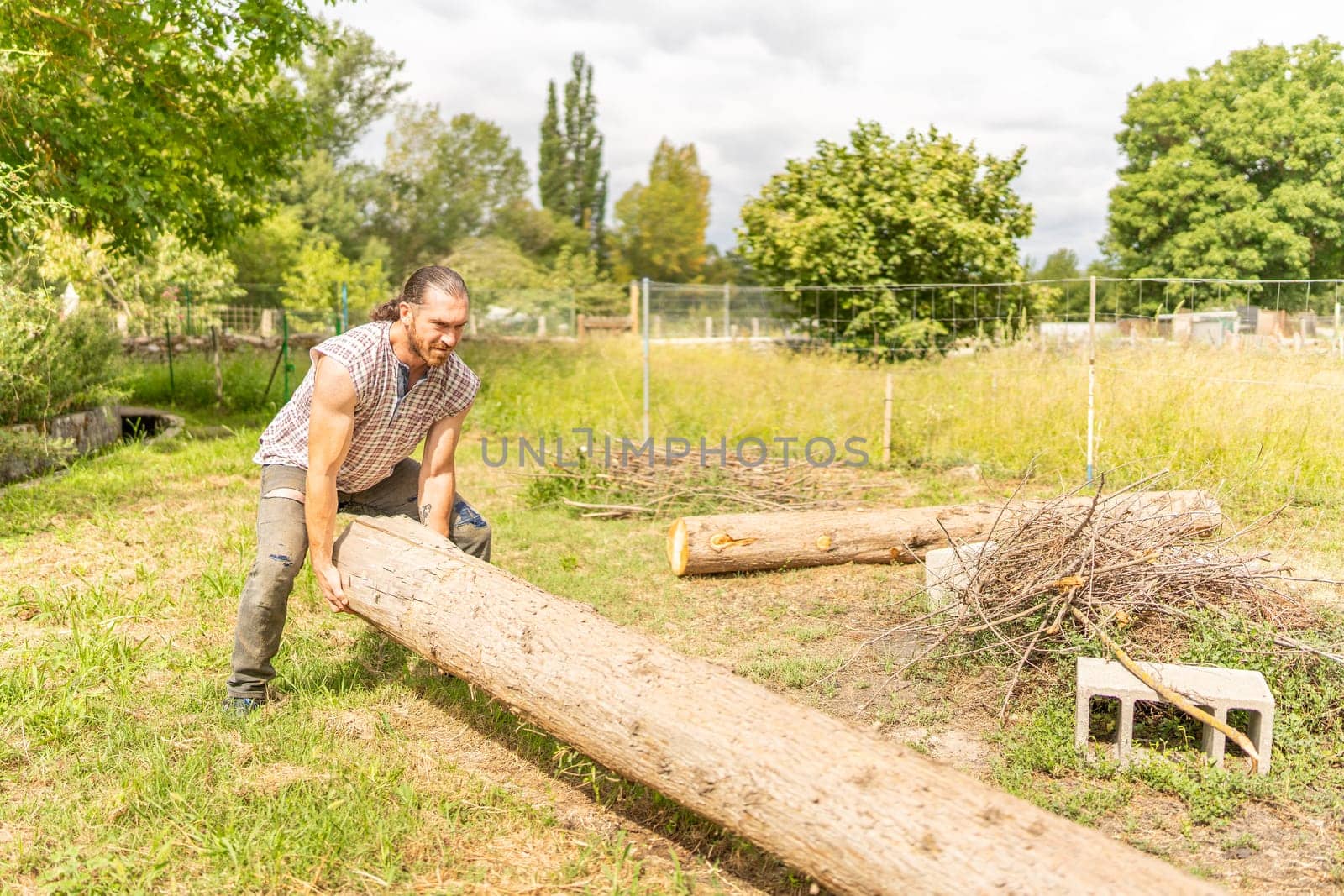 Portrait of a male woodcutter lifting a log with his bare hands in a field