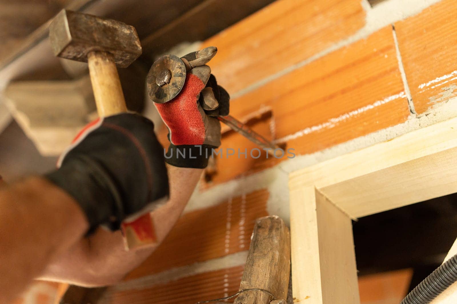 Detail of the hands of a man cutting a hole in the wall to put in wiring
