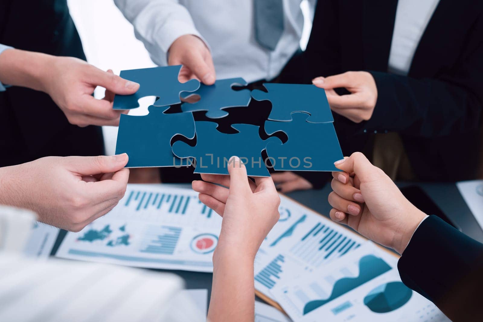 Closeup top view business people join jigsaw puzzle together in harmony office by biancoblue