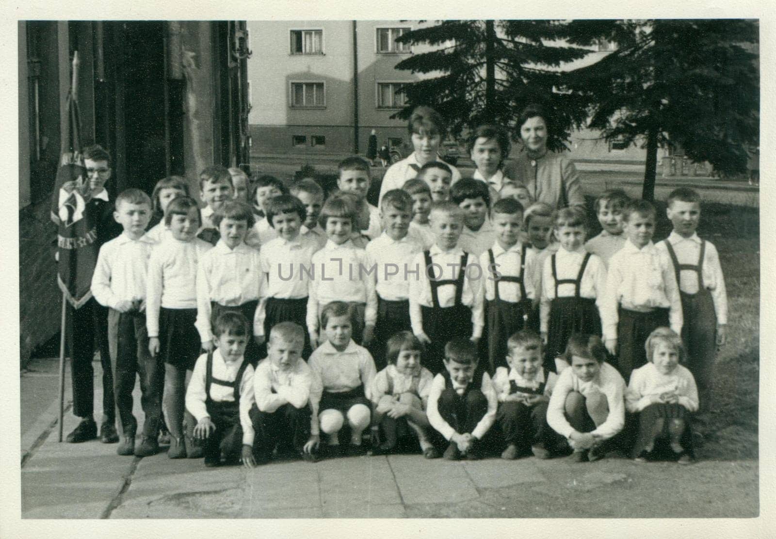 Retro photo shows small pupils and they female teachers - schoolmistresses pose for photograper outside. Vintage black and white photography. by roman_nerud