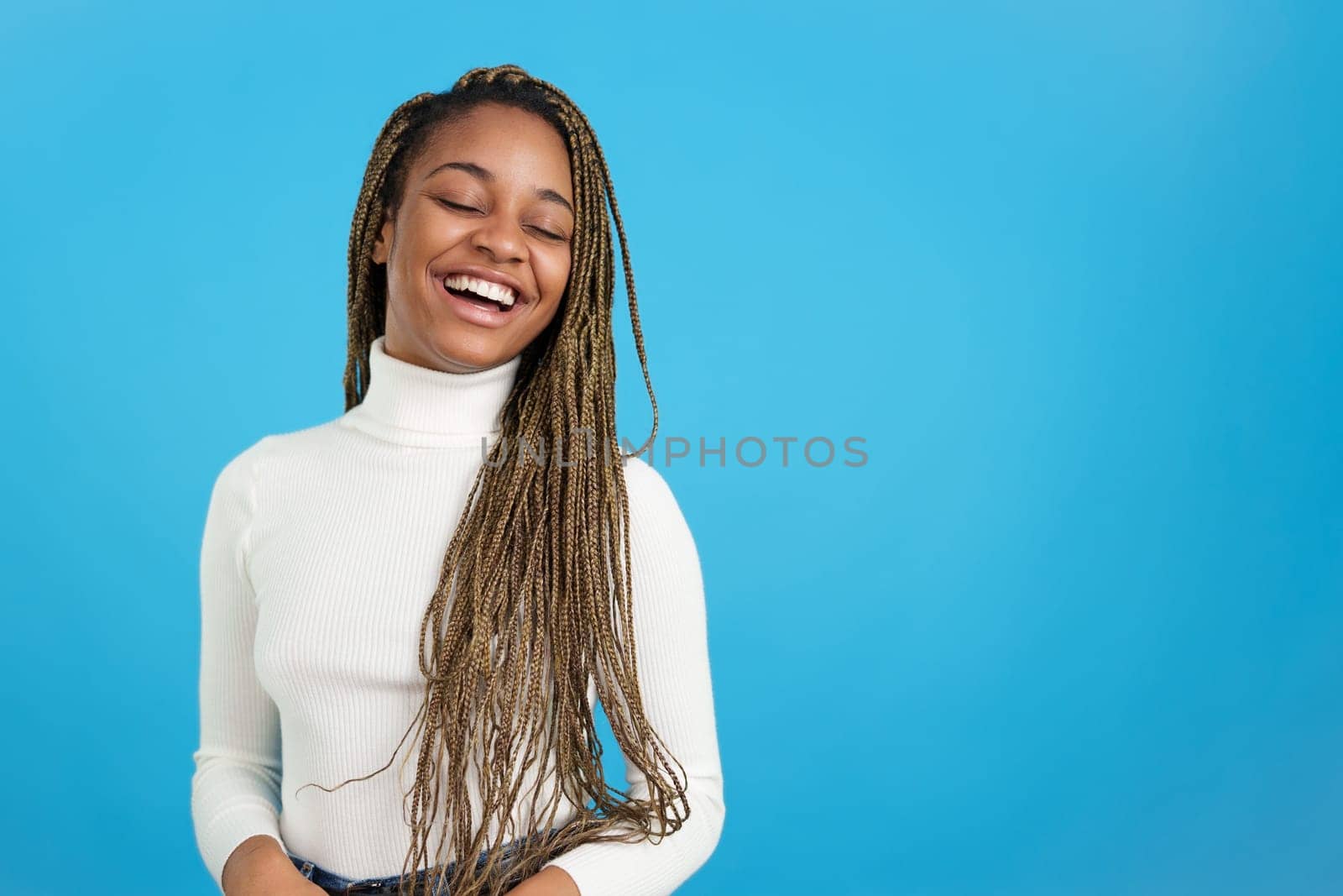 Studio portrait with blue background of a happy african woman with braids closing the eyes