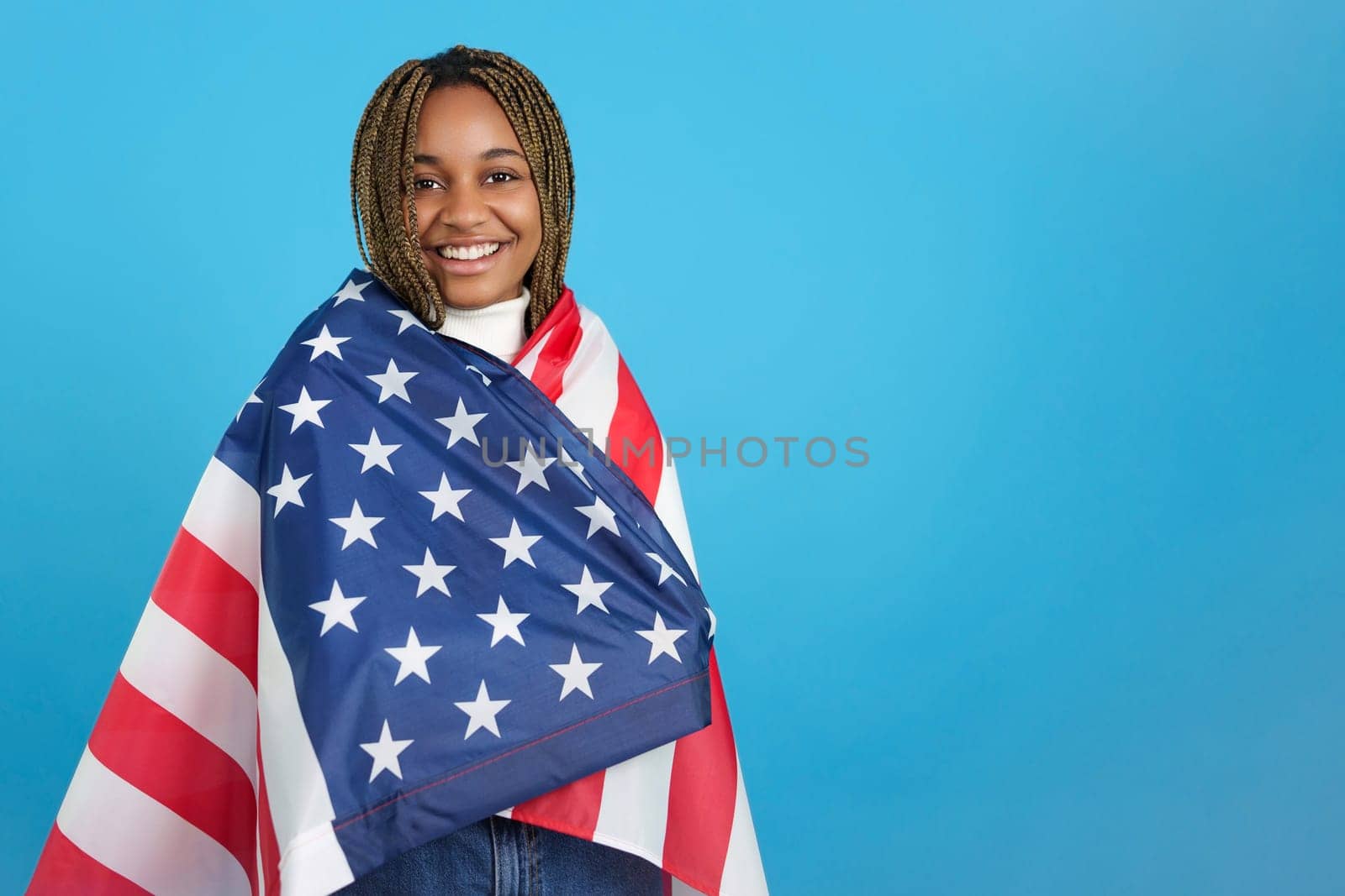 Studio portrait with blue background of an african woman wrapped in an american flag