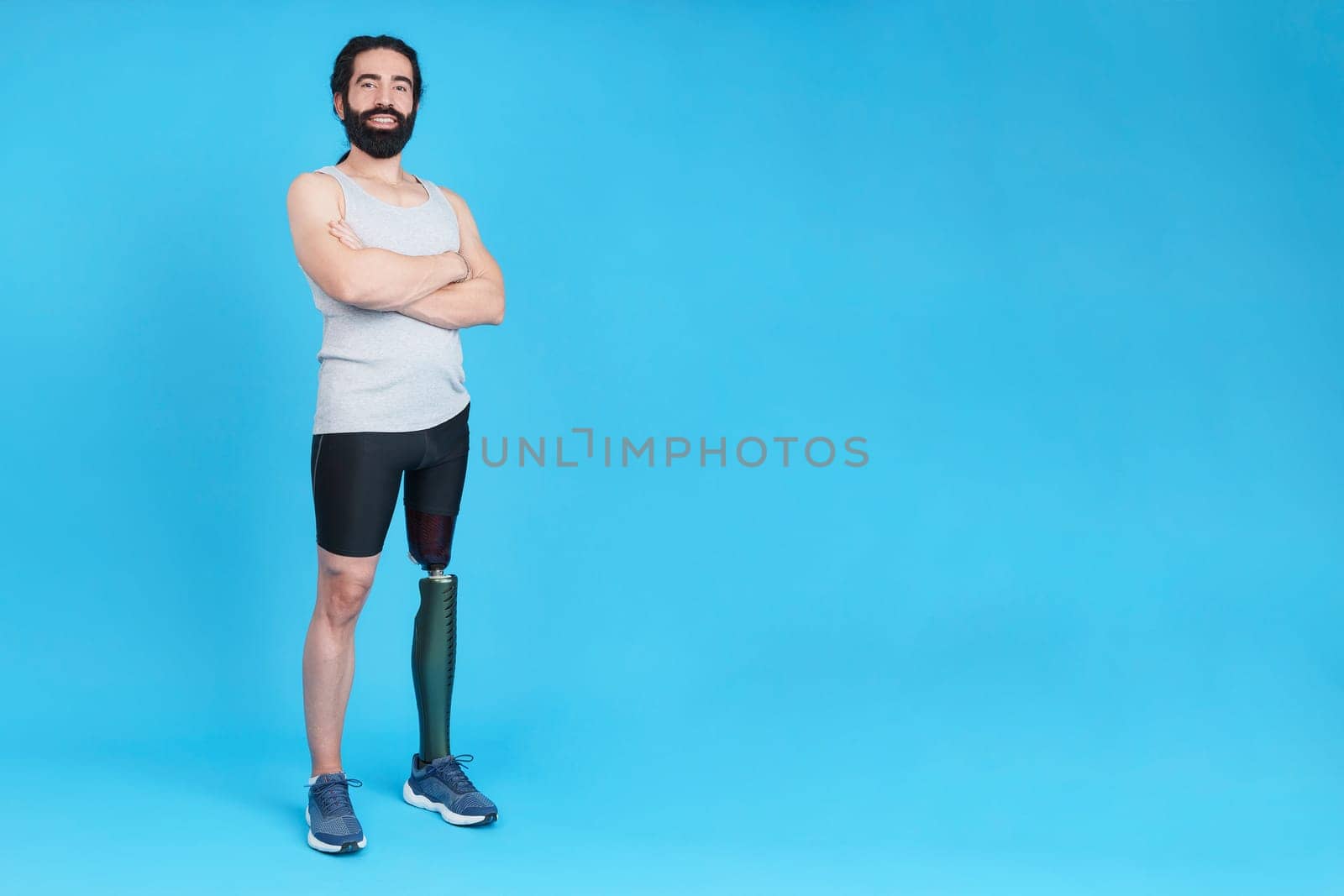 Studio portrait with copy space and blue background of a caucasian sportive man standing with a prosthesis on his leg