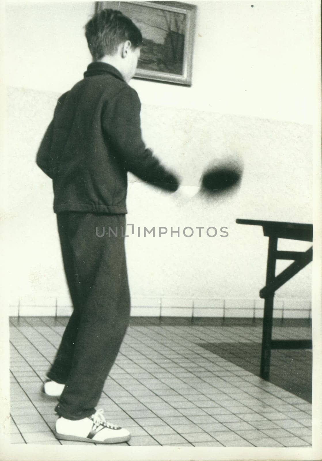Retro photo shows young boy plays table tennis - ping-pong. Vintage black and white photography. by roman_nerud