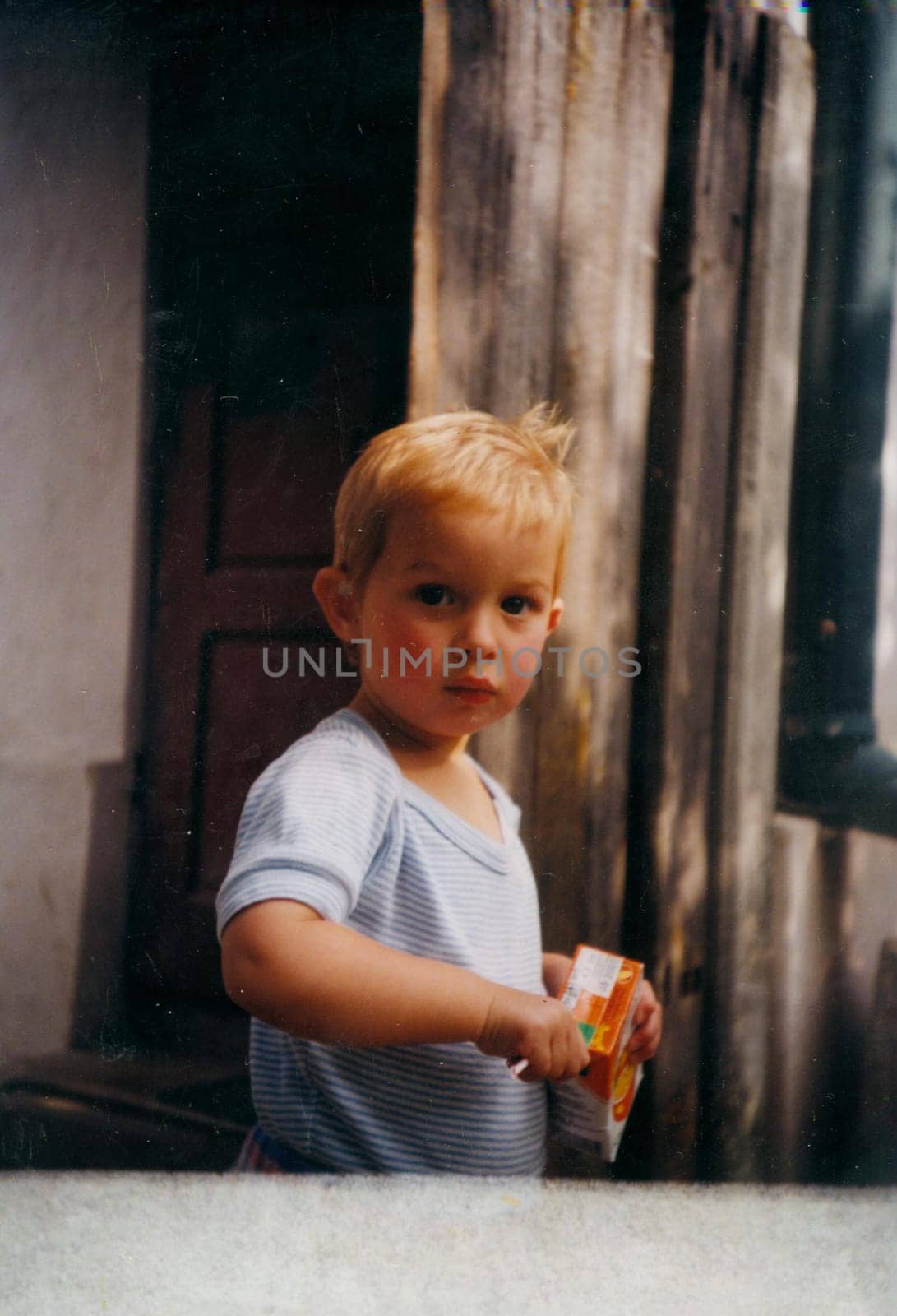 Retro photo shows cute small boy with open juice box. Vintage color photography. by roman_nerud