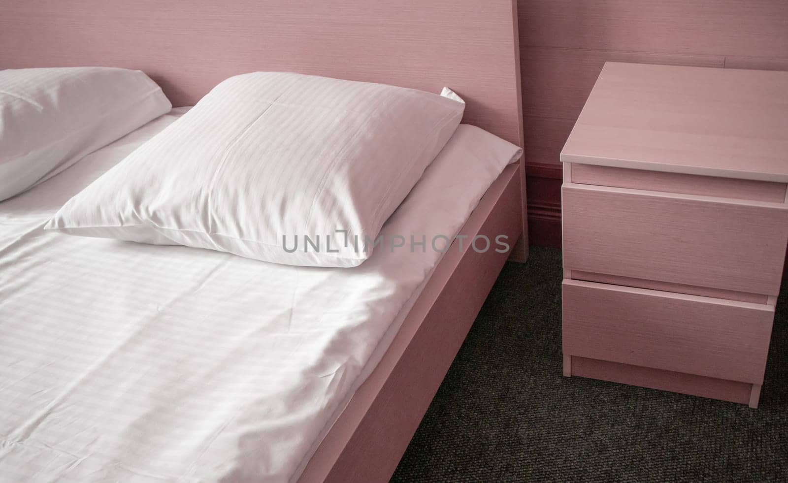 Soft pink tinting, close-up of the bed and bedside table, modern interior of the bedroom in the hotel by claire_lucia