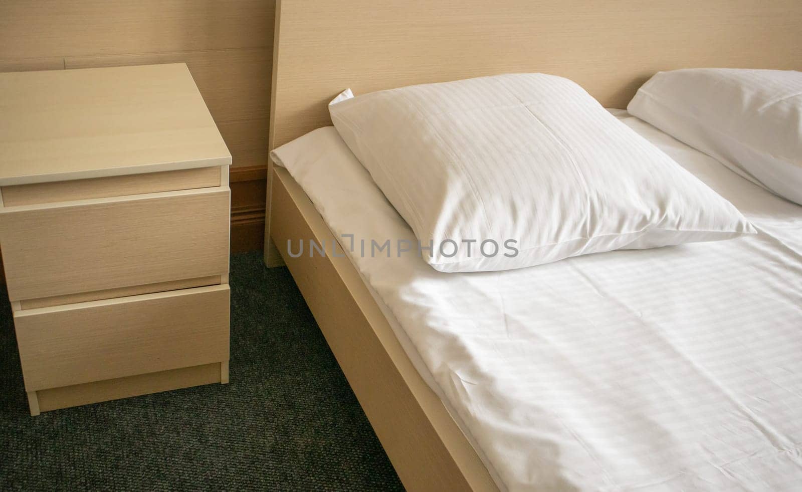 Close-up of the bed and bedside table, modern and bright interior of the bedroom in the hotel.