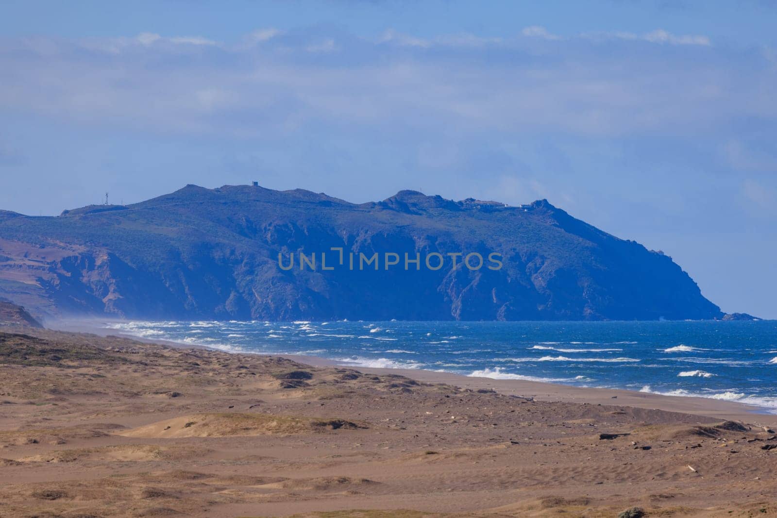 Deserted sandy beach with distant cliffs in Point Reyes, California on sunny day. High quality photo