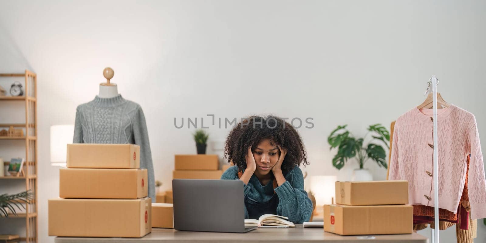 Stressed young entrepreneur African American woman and courier parcel box at home office. Small business owner, online market delivery, lifestyle freelance concept.