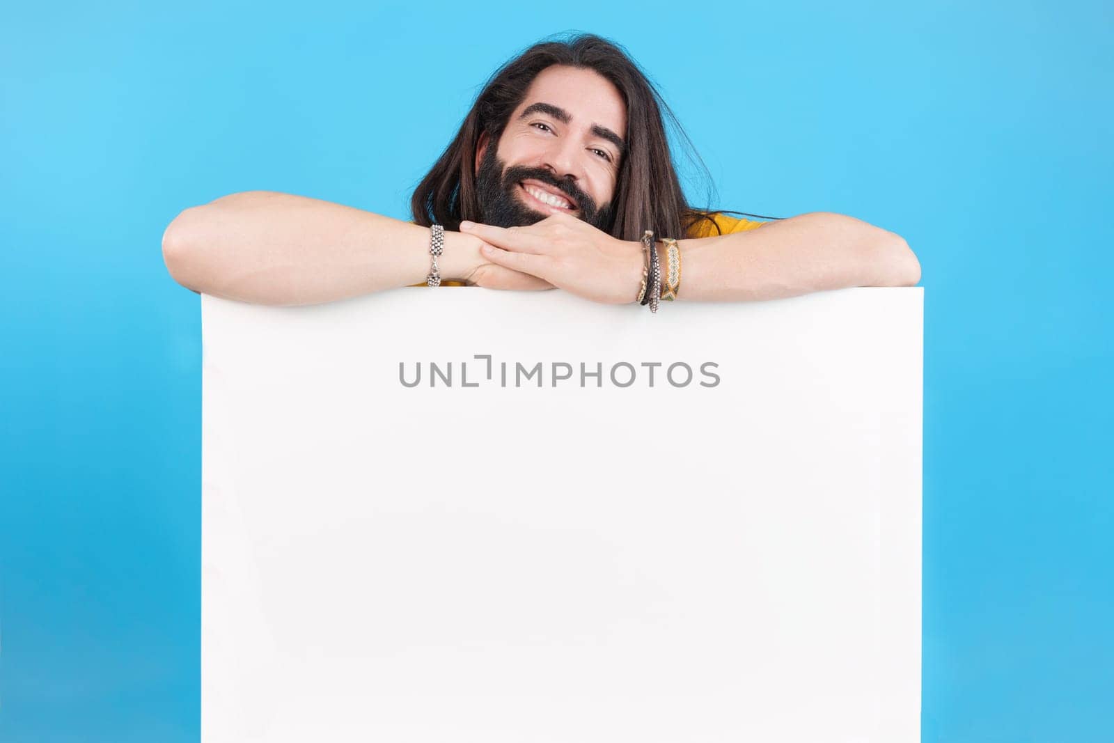 Studio portrait of a happy smiley man with long hair holding a board with blank space