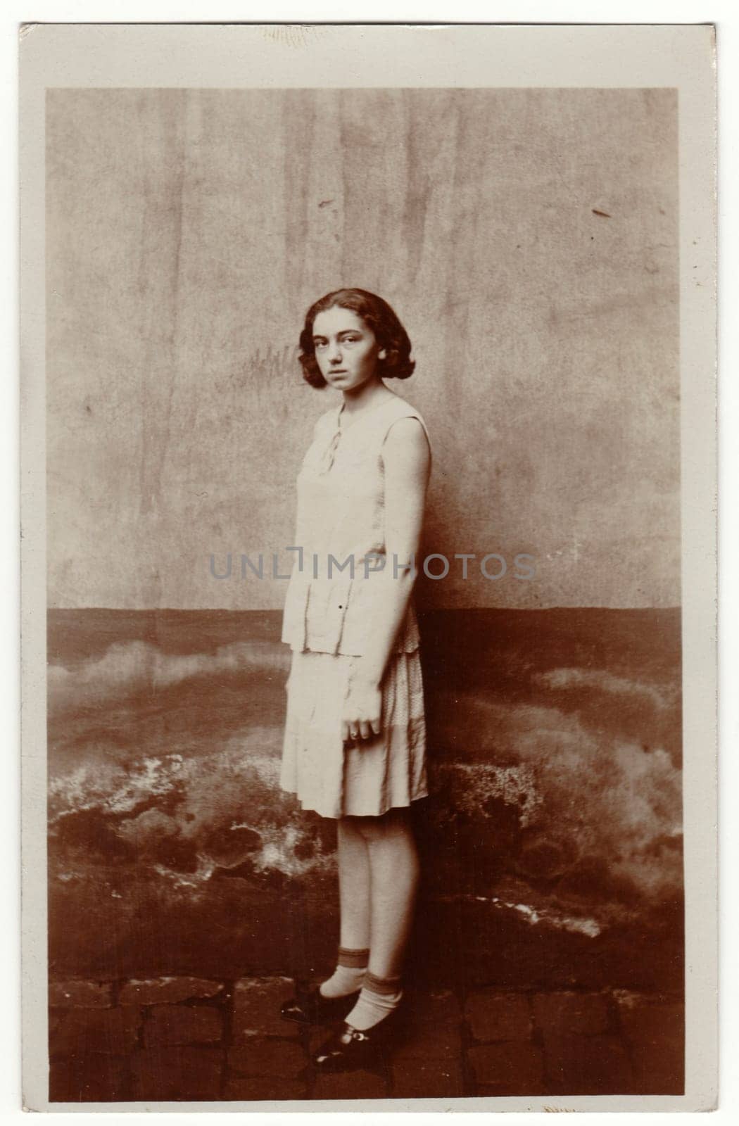 Vintage photo shows young girl stands outside. She wears a light dress. Retro black and white photography. by roman_nerud